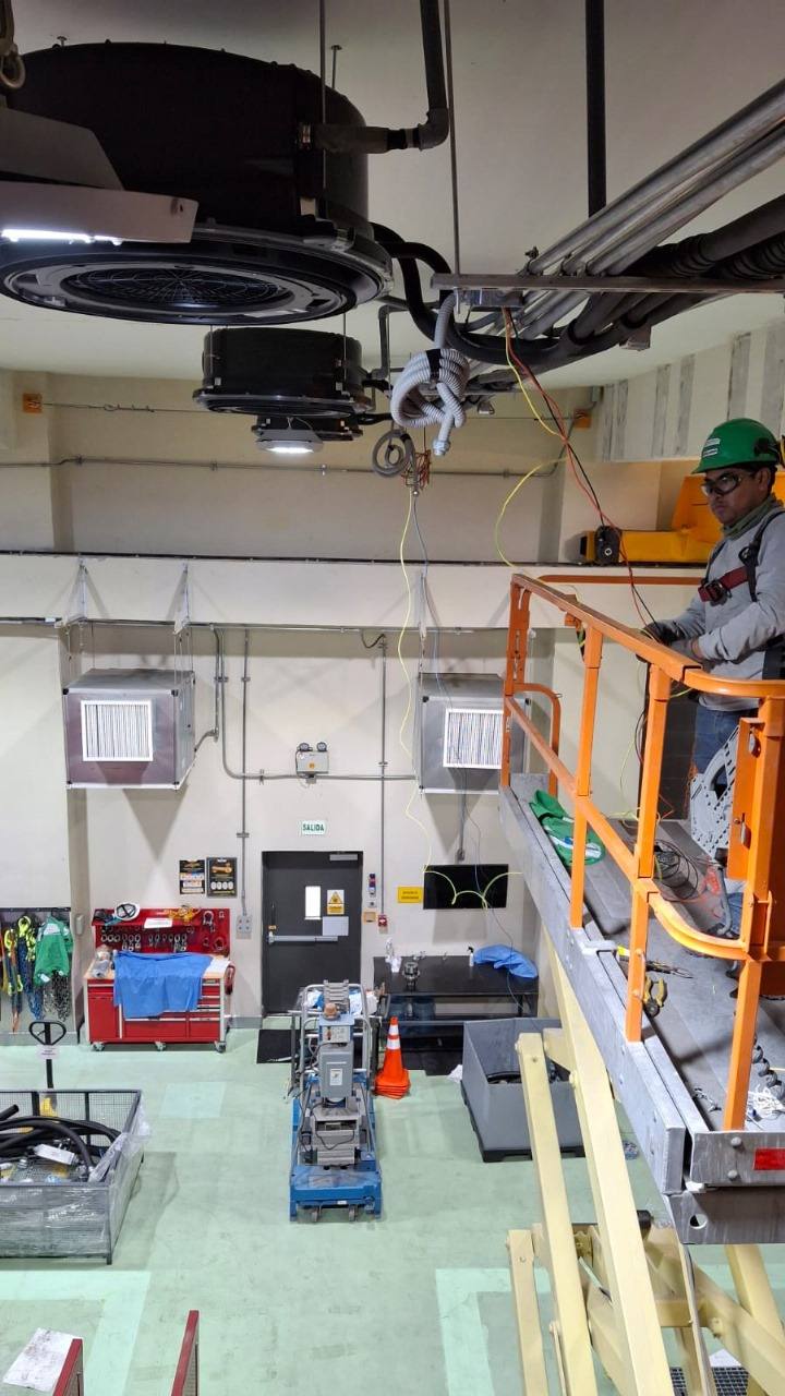 Técnico sobre plataforma elevadora instalando equipos en una nave
